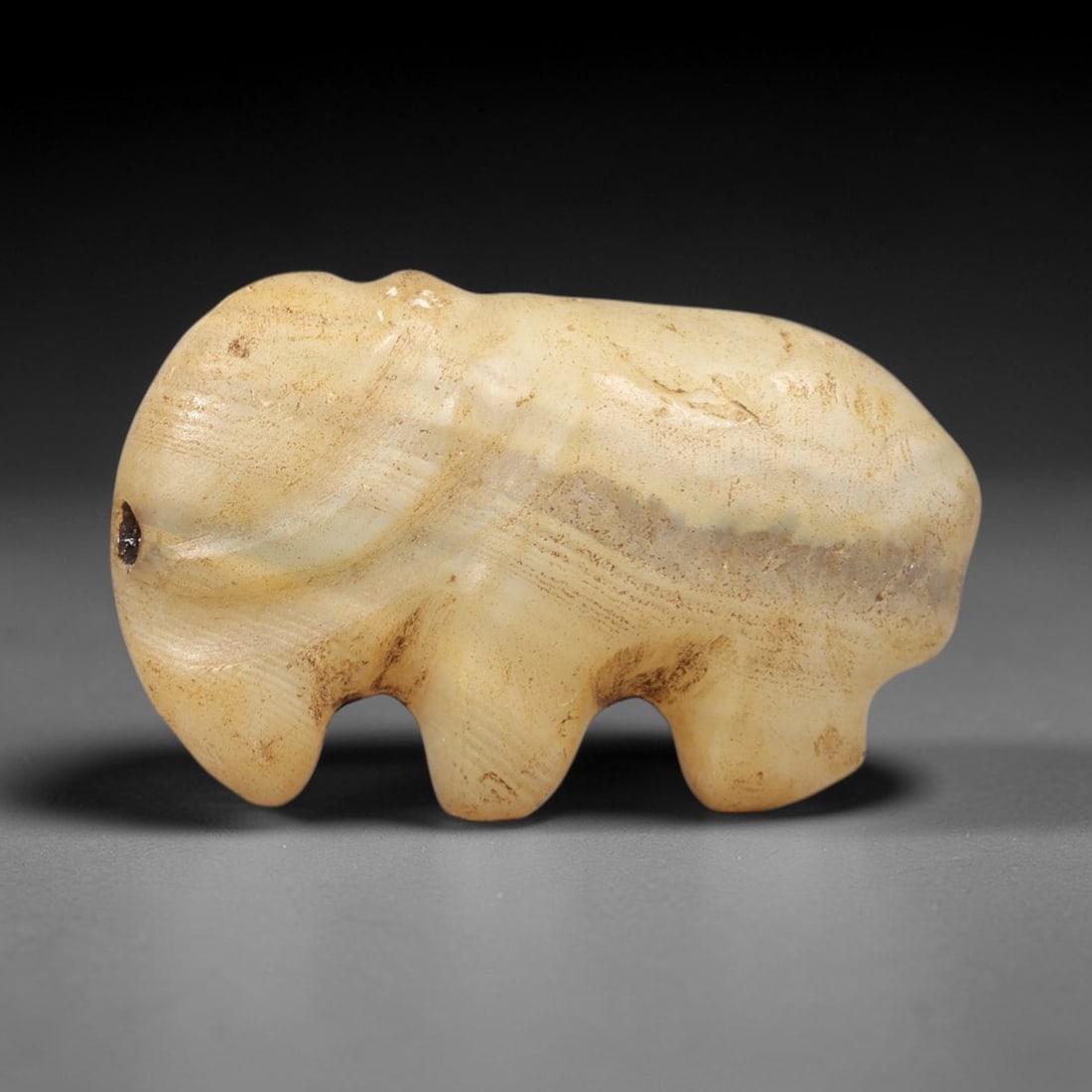Ancient Banded Agate Elephant - Near Eastern Amulet Figurine, 44AS: This amulet is carved from banded agate, exhibiting a creamy base with subtle horizontal banding and earthy patina consistent with ancient Near Eastern burial contexts. The form depicts a stylized ele