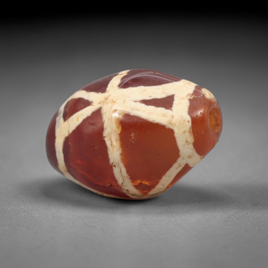 Ancient Carnelian Etched Dzi Bead - Himalayan Amulet, 78XV: Crafted from rich translucent carnelian, this bead features bold etched white intersecting linear patterns, executed in the traditional Himalayan Dzi bead technique. The form is a compact ovoid shape