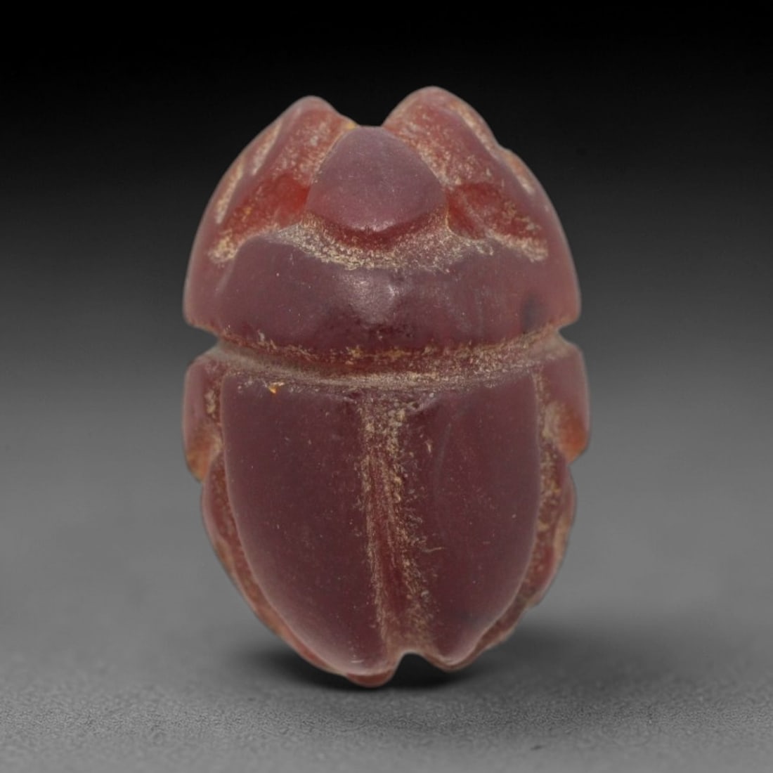 Ancient Carnelian Scarab - Egyptian Amulet Bead, 75XS: This amulet is carved from rich deep red carnelian, exhibiting natural translucency and a warm, matte finish characteristic of ancient Egyptian glyptic craftsmanship. The form is a classic scarab beet