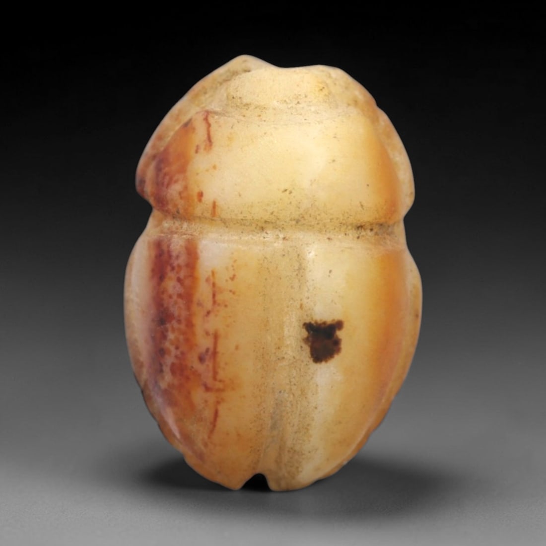 Ancient Polychrome Stone Scarab Amulet - Egyptian Pendant, 52ZW: This amulet is carved from a mottled cream and amber-toned stone, depicting a classic scarab beetle form with distinct elytra divisions and a rounded head. Subtle traces of pigment remain in the carve
