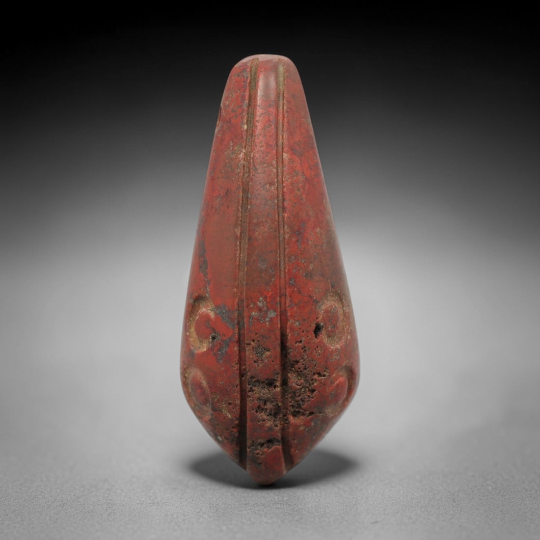 Ancient Near Eastern Red Stone Teardrop Amulet - Carved Pendant Figure, 58ZV: This amulet is carved from a rich, deep red stone with natural speckling and mineral inclusions, likely brecciated jasper or hematite, featuring an elegant teardrop form. The piece is defined by two p