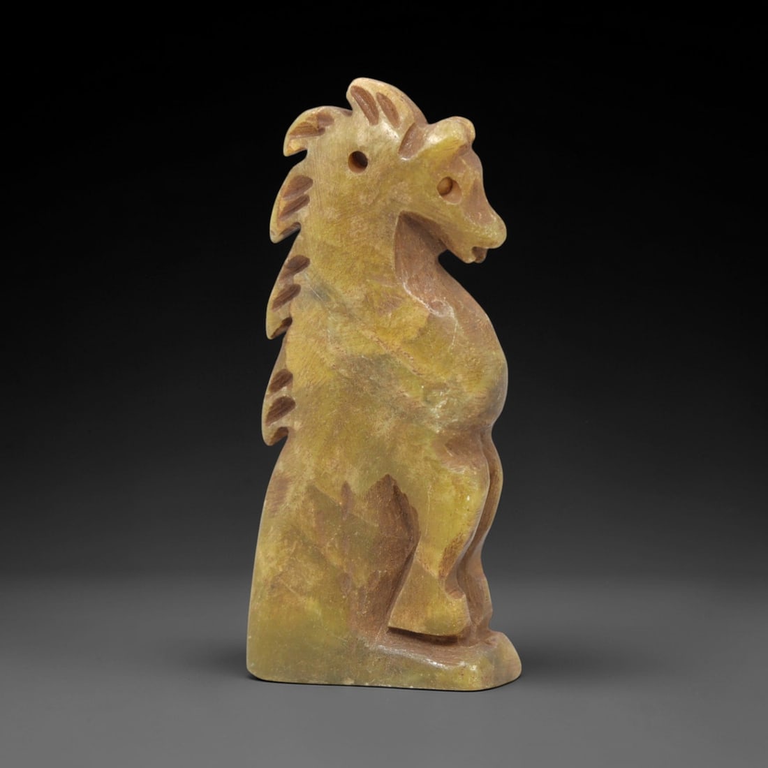 Ancient Serpentine Horse - Near Eastern Amulet, 41XV: Carved from serpentine, this horse amulet is rendered in a stylized upright form with distinct incised details defining the mane and facial features, and a drilled suspension hole consistent with wear