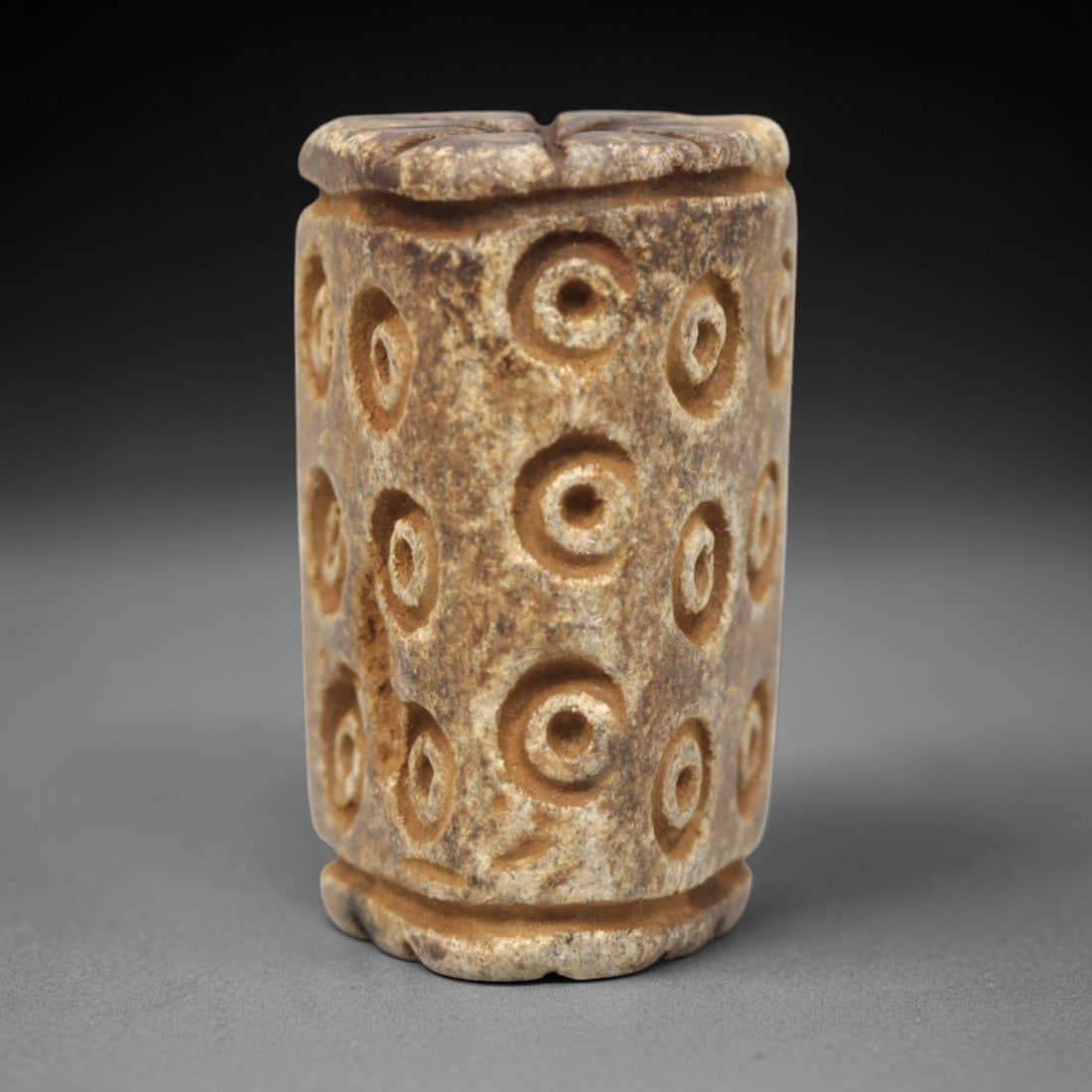 Ancient Steatite Amulet Bead - Near Eastern Concentric Circles, 14XV: Carved from steatite, this ancient amulet bead takes a cylindrical form, featuring a vertical suspension hole at the top for wearable use. Its surface is adorned with a vertical arrangement of concent