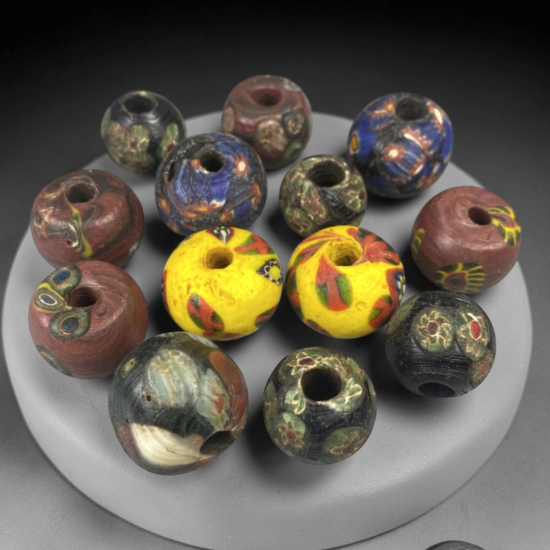 Antique Venetian Glass Beads - 13 Pieces, 58FX: This set of 13 antique Venetian glass beads features hand-formed spherical shapes, crafted from polychrome glass with intricate mosaic and cane-work patterns characteristic of traditional Venetian gla