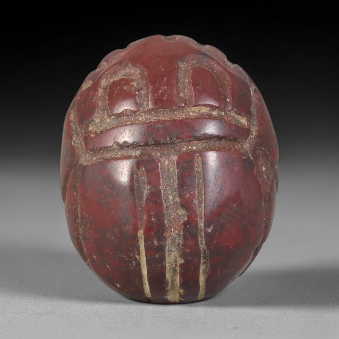 Ancient Jasper Scarab Amulet - Egyptian Figurine, 61AP: This artifact is carved from deep red jasper, exhibiting a smooth, polished surface with natural mineral veining and faint surface wear consistent with age. The form is a classic scarab amulet, with a