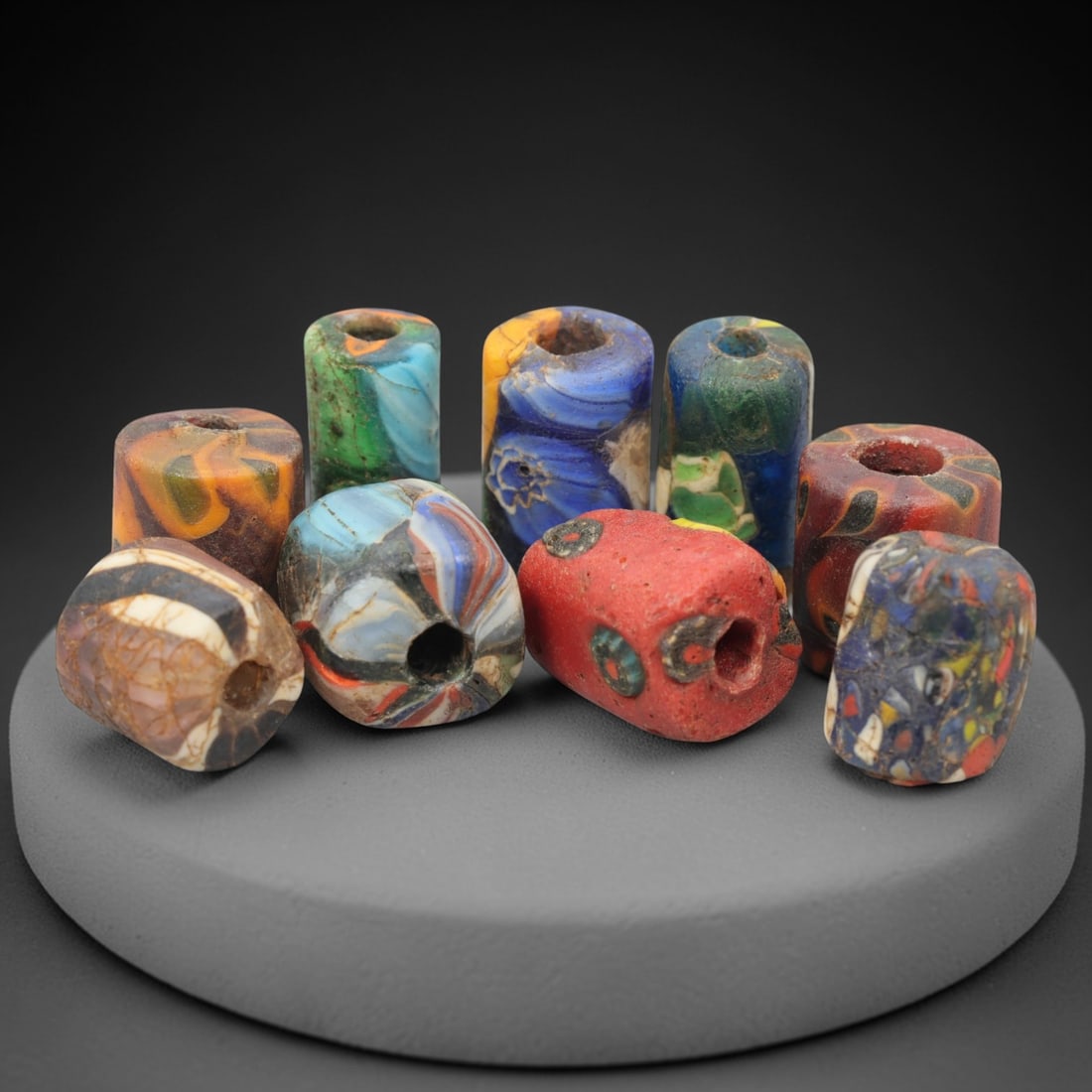 A Group of Venetian Cylindrical and Spherical Mosaic Glass Beads, 19th-20th Century, 96ZM: Fabricated from opaque and translucent glass, the group consists of ten beads combining cylindrical and spherical forms, each with a central perforation for suspension. Examples include a bead with a