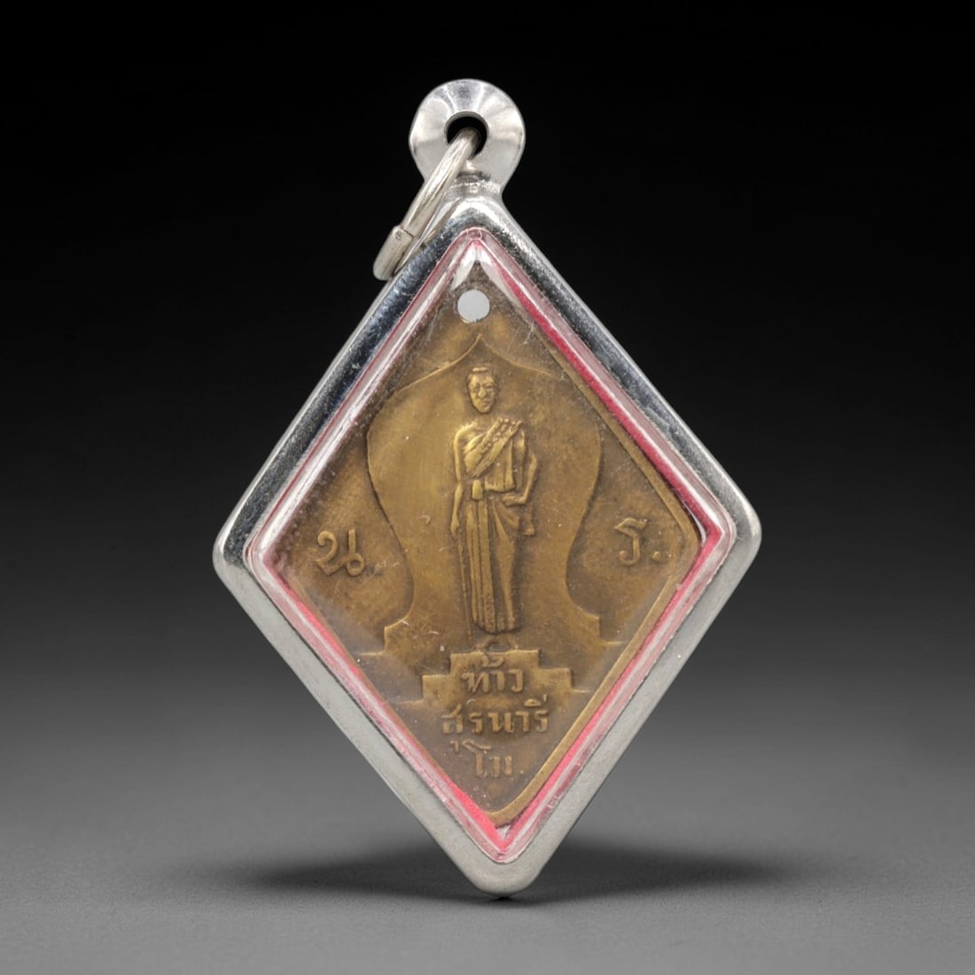 A Thai Monk Commemorative Bronze Amulet in Silver-Tone Case, 20th Century, 8ZK: This diamond-shaped amulet is cast from bronze and housed in a modern silver-tone metal case with a red enamel border and a suspension loop at the apex. The obverse features a raised relief of a Thai