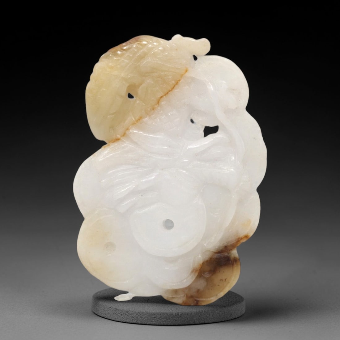 A Chinese Jadeite Jade Dragon and Coin Pendant Plaque, 20th Century, 37FR: Carved from predominantly white jadeite jade with prominent honey-brown and russet inclusions concentrated on the upper and lower sections, the pendant is formed as an irregularly shaped, lobed plaque