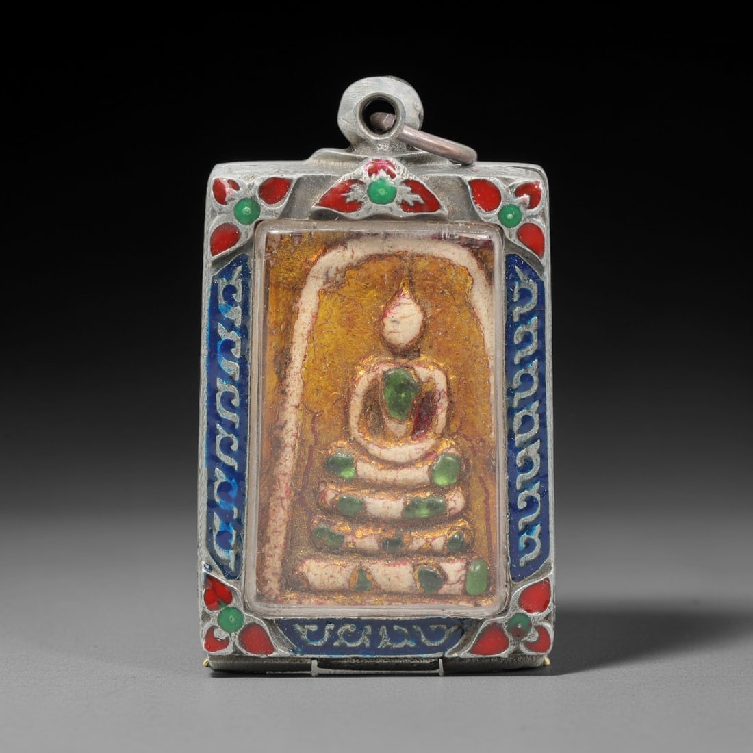 A Thai Terracotta Buddha Amulet in Metal Case, 20th Century, 78ZH: The amulet is formed from terracotta, overlaid with a gold-toned leaf layer on both obverse and reverse surfaces. The obverse bears a molded relief of a seated Buddha in meditative posture on a tiered