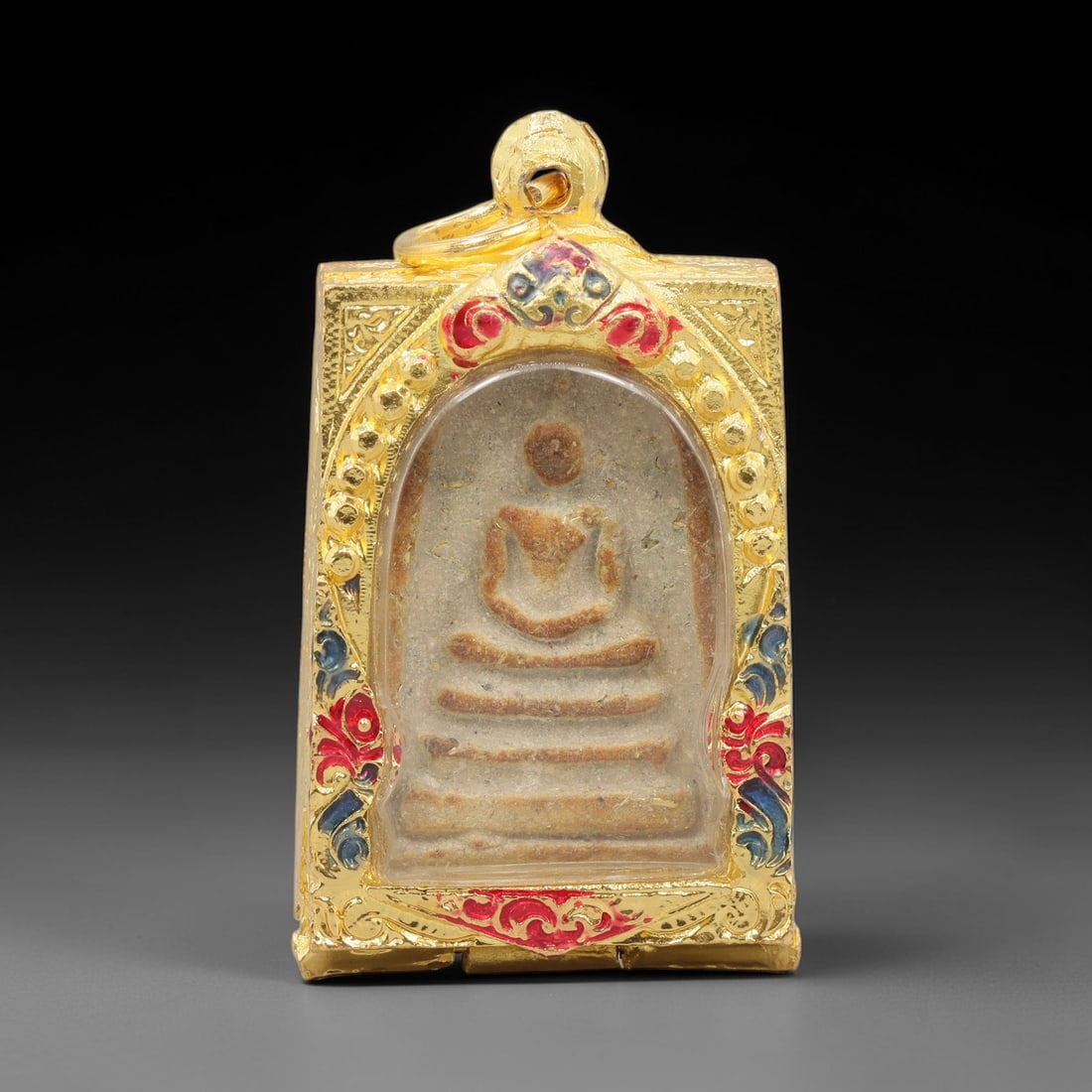 A Thai Terracotta Buddha Amulet in Metal Case, 20th Century, 68ZH: The amulet is formed from terracotta, with a light beige matrix containing visible particulate inclusions and surface discoloration. The obverse depicts a seated Buddha in meditative posture, seated o