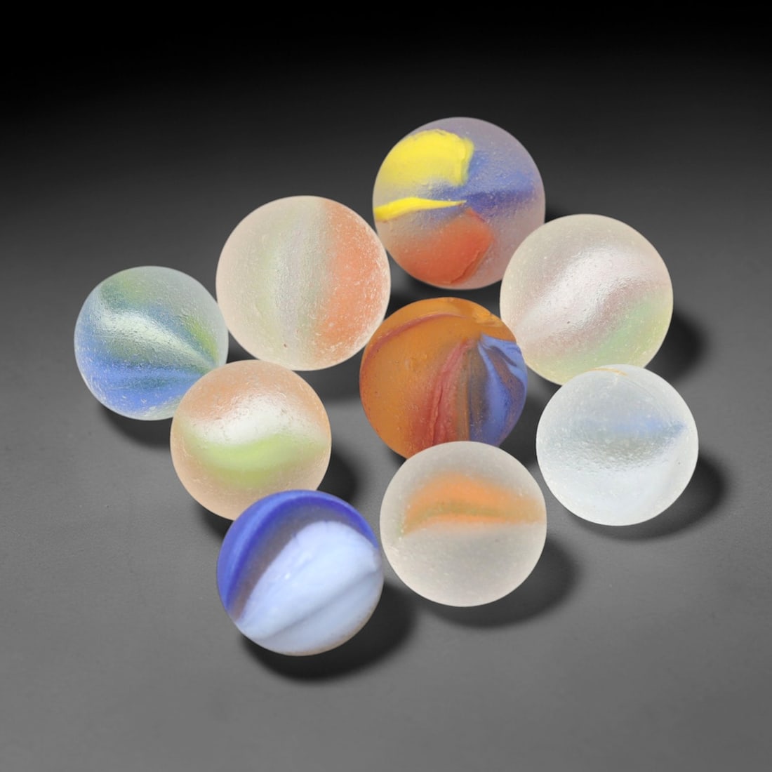 Vintage Glass Marbles - Swirled Frosted Set, 100XS: Crafted from frosted glass, this set of nine vintage marbles features swirled color patterns in hues of blue, green, orange, yellow, and white, each with a matte, weathered surface. The spherical form