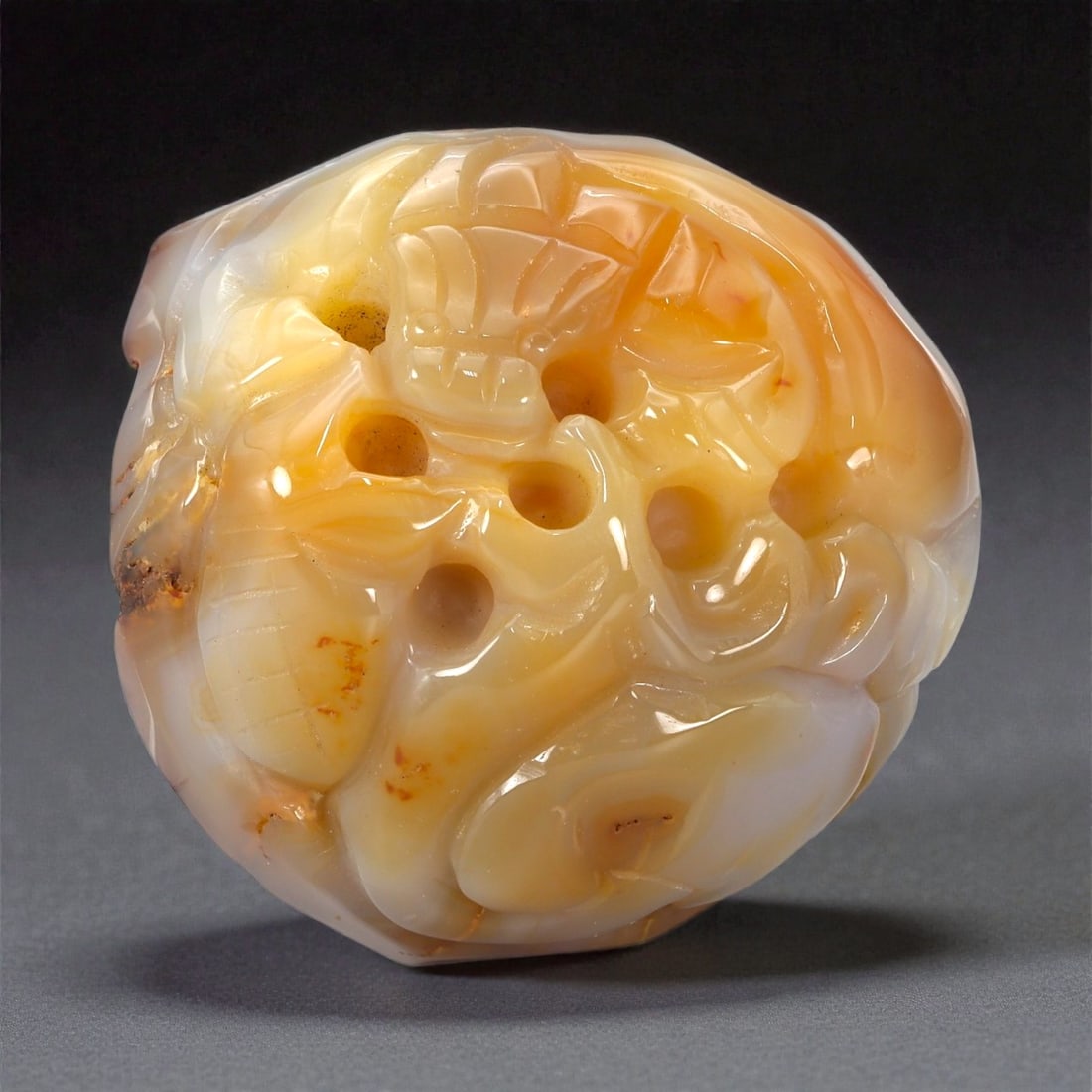 A Chinese Chalcedony Pebble Carving, 20th Century, 20YB: Carved from translucent chalcedony displaying natural white and honey-toned banding with areas of iron-oxide staining, the object is worked from a rounded pebble form retaining its organic outline. Th