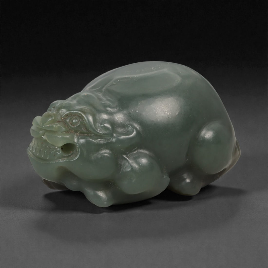 Chinese Jade Pixiu Beast - Carved Stone Animal, 58ZD: Carved from translucent green jade with soft tonal variation, this compact pixiu is modeled in a crouching pose with rounded haunches, a stylized head, and lightly incised details defining the eyes, m