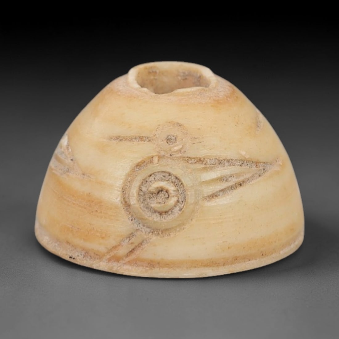 Ancient Bone Spindle Whorl - Near Eastern Spiral Motif, 83XR: This ancient Near Eastern spindle whorl is crafted from bone, featuring incised spiral and linear geometric decoration surrounding the central aperture. The compact, rounded form is a traditional text