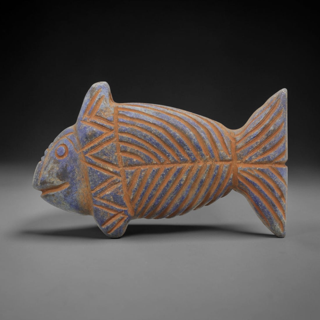 Ancient Lapis Fish Amulet - Near Eastern Carved Figurine, 79ZT: Carved from lapis lazuli, the amulet takes the form of a stylized fish, rendered in flat relief with incised geometric and linear decoration. The body is segmented with incised lines to represent scal
