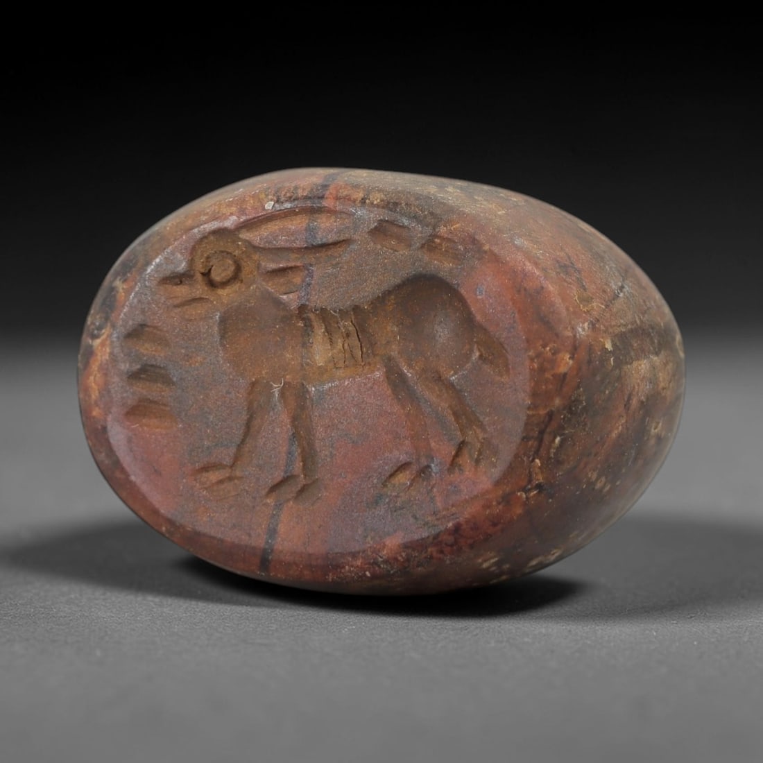 Ancient Steatite Hemispherical Stamp Seal - Animal Motif, 20AH: Carved from steatite, this ancient hemispherical stamp seal features a raised relief of a stylized animal motif on the upper surface. The stone exhibits a muted earthy hue with natural inclusions, typ