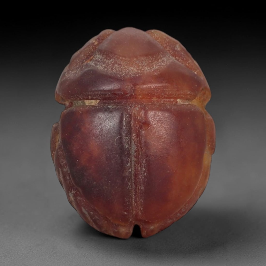 Ancient Carnelian Scarab Amulet - Egyptian Figurine, 72AJ: Carved from rich, deep red carnelian with subtle amber undertones, this amulet is formed as a stylized scarab beetle with clean linear detailing to define segmented wing cases and body contours, consi
