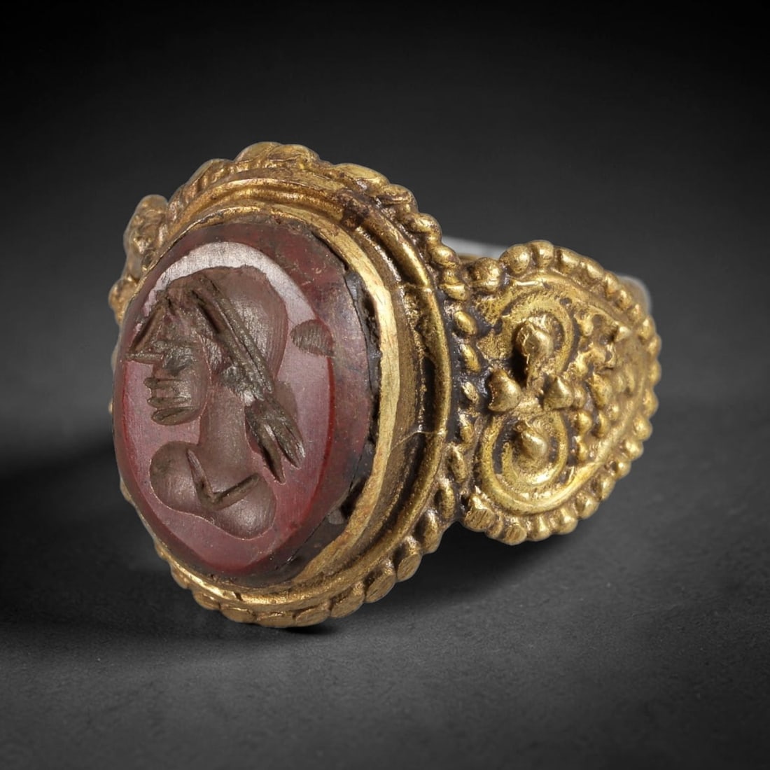 Antique Qajar Dynasty Carnelian Intaglio Brass Ring - Size 10 US, 88BA: Crafted from brass, this ring features an oval carnelian intaglio panel carved with a profile figure, executed in the distinctive Qajar style. The brass band displays ornate, relief-carved metalwork w