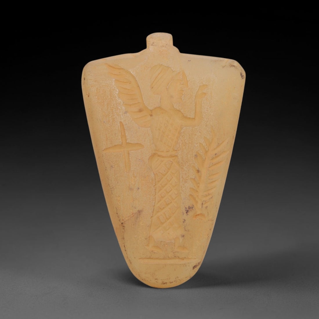 Ancient Chalcedony Amulet - Near Eastern Winged Figure, 80ZT: Carved from chalcedony, this amulet features a relief depiction of a winged humanoid figure, likely a deity or spirit, rendered in the stylized glyptic tradition of the ancient Near East. The figure i