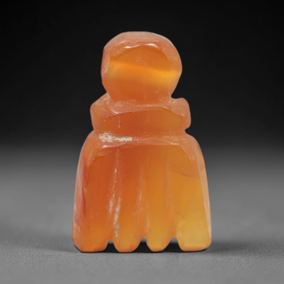 Ancient Agate Fist - Near Eastern Amulet Figurine, 78XS: This amulet is carved from warm orange agate, displaying natural banding and a smooth, glossy finish typical of ancient Near Eastern glyptic craftsmanship. The form is a stylized fist, with defined kn