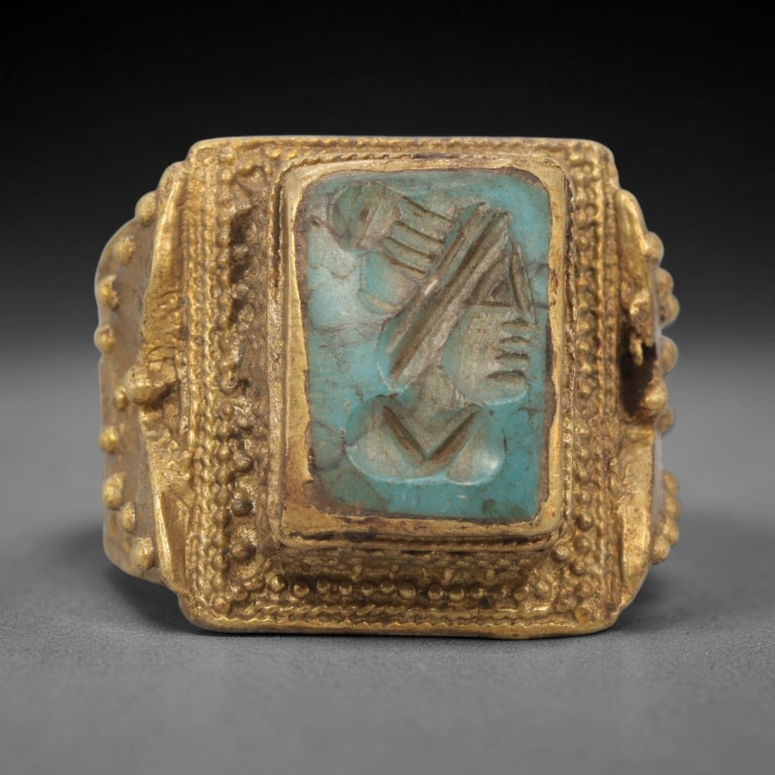 Antique Qajar Dynasty Turquoise Intaglio Ring - Size 11 US, 5WJ: Crafted from brass with a substantial square bezel, this ring features a carved turquoise intaglio stone at its center, depicting an incised profile portrait motif characteristic of Qajar-era Persian
