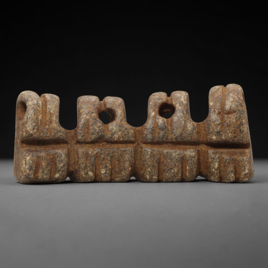Ancient Steatite Amulet - Near Eastern Ritual Figurine, 87FW: Carved from a fine-grained steatite, this Near Eastern amulet features a segmented, linear form with four distinct arched sections, each punctuated by drilled suspension holes and defined by incised l