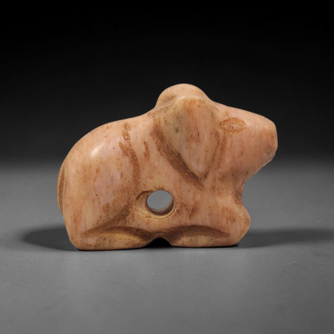 Ancient Stone Rodent Amulet - Near Eastern Figurine, 92XV: This amulet is carved from a pale pinkish stone with natural earthy veining and a smooth, worn patina across its surface, executed in a simplified, stylized manner that emphasizes the recumbent rodent