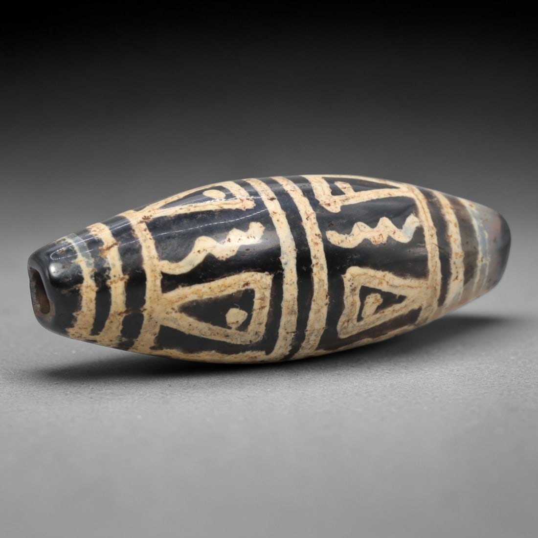 Ancient Agate Etched Dzi Bead - Himalayan Amulet, 75XV: Crafted from dark translucent agate, this bead displays elaborate etched white geometric and stylized symbolic motifs, including triangular forms and wavy linear bands, executed in the traditional Him