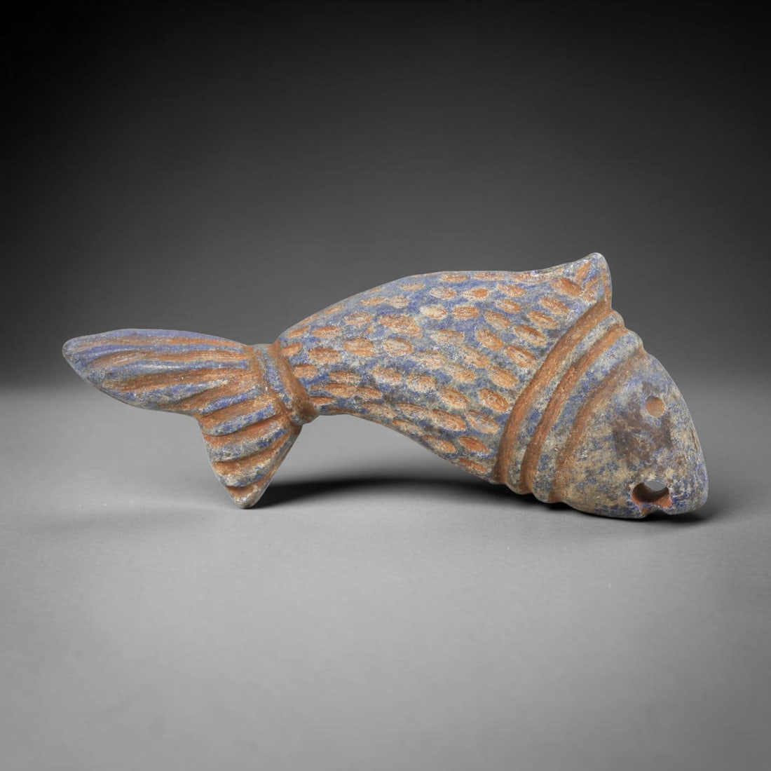 Ancient Lapis Lazuli Fish Amulet - Near Eastern Carving, 55FY: Carved from lapis lazuli, the amulet is fashioned in the form of a stylized fish, with two suspension holes drilled through the head for wear as a protective talisman. The figure is detailed with inci
