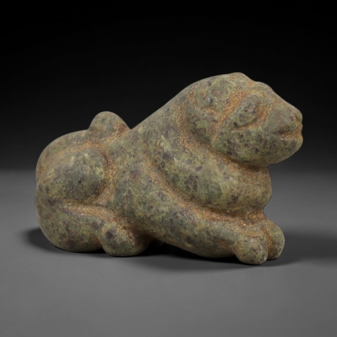Ancient Mottled Green Stone Recumbent Feline - Near Eastern Amulet, 90AD: Carved from mottled green stone with fine purple and tan speckling, this amulet depicts a recumbent feline in a compact, stylized form. The creature is rendered in a prone resting posture, with simpli