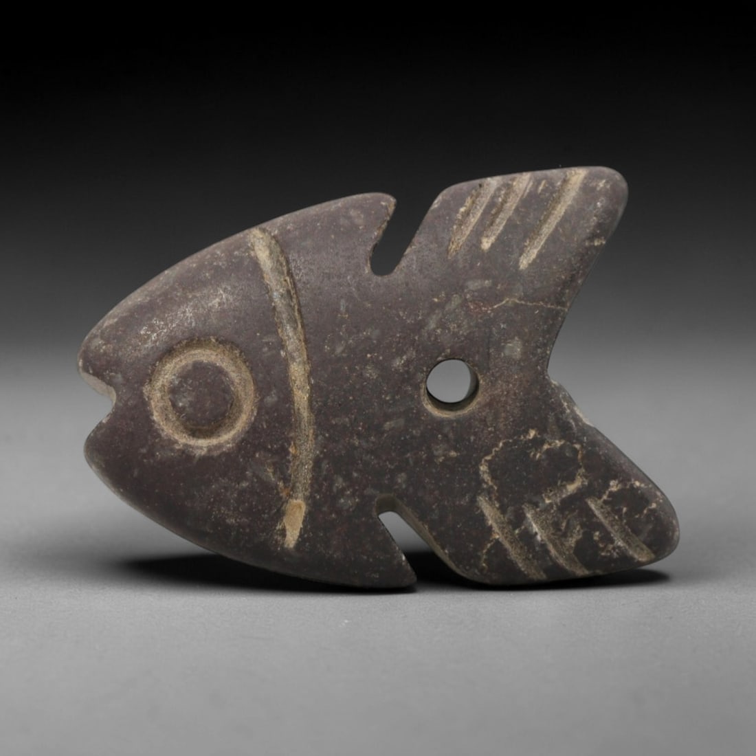 Ancient Dark Stone Fish Amulet - Egyptian Animal Figure, 77ZW: This amulet is carved from a mottled dark stone, depicting a stylized fish with incised details defining the eye, fins, and body contours. A perforation is drilled near the center of the body for susp