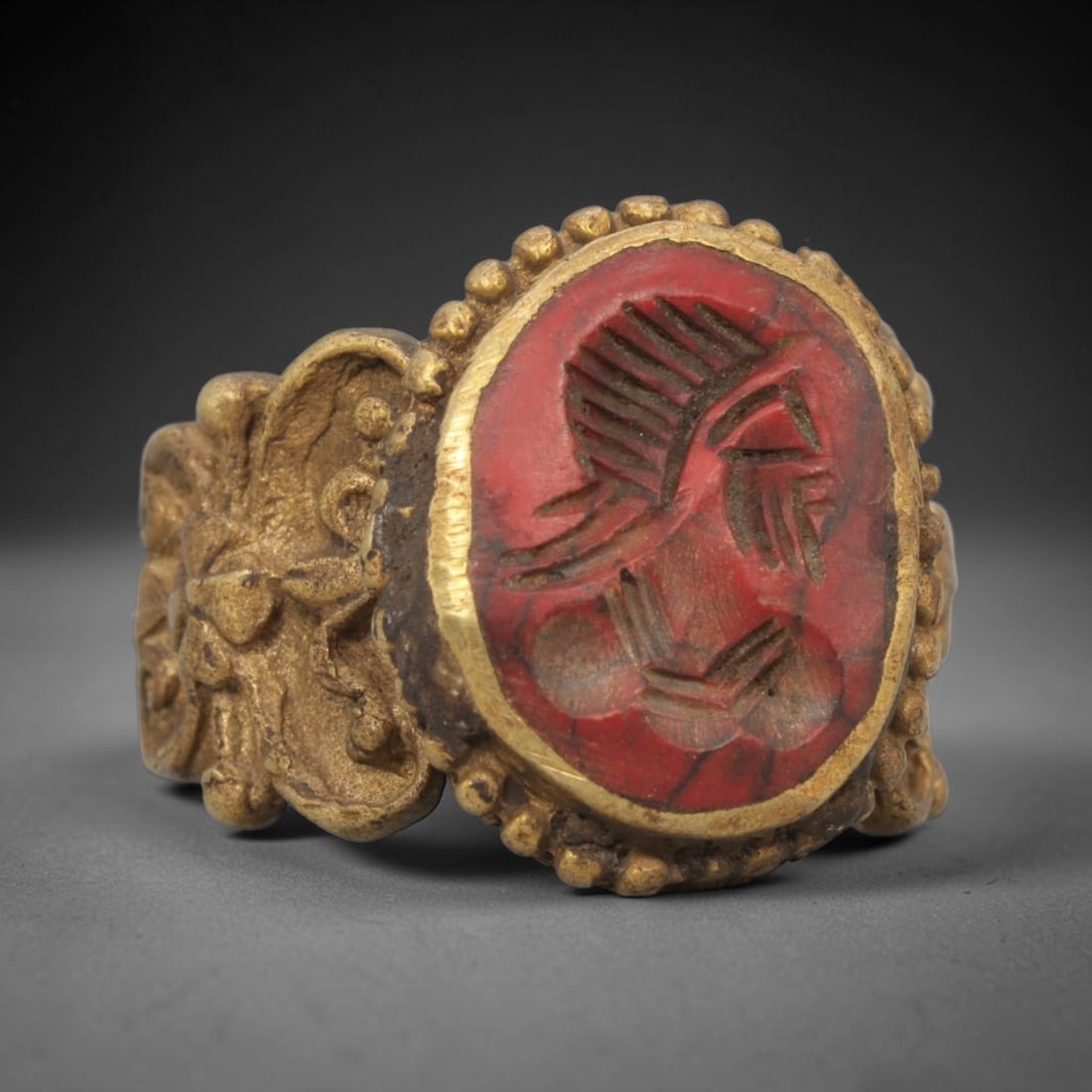Antique Qajar Dynasty Carnelian Intaglio Ring - Size 9 US, 99ZX: Crafted from gilt brass with an ornate oval bezel, this ring features a carved carnelian intaglio stone at its center, depicting an incised profile portrait motif characteristic of Qajar-era Persian s