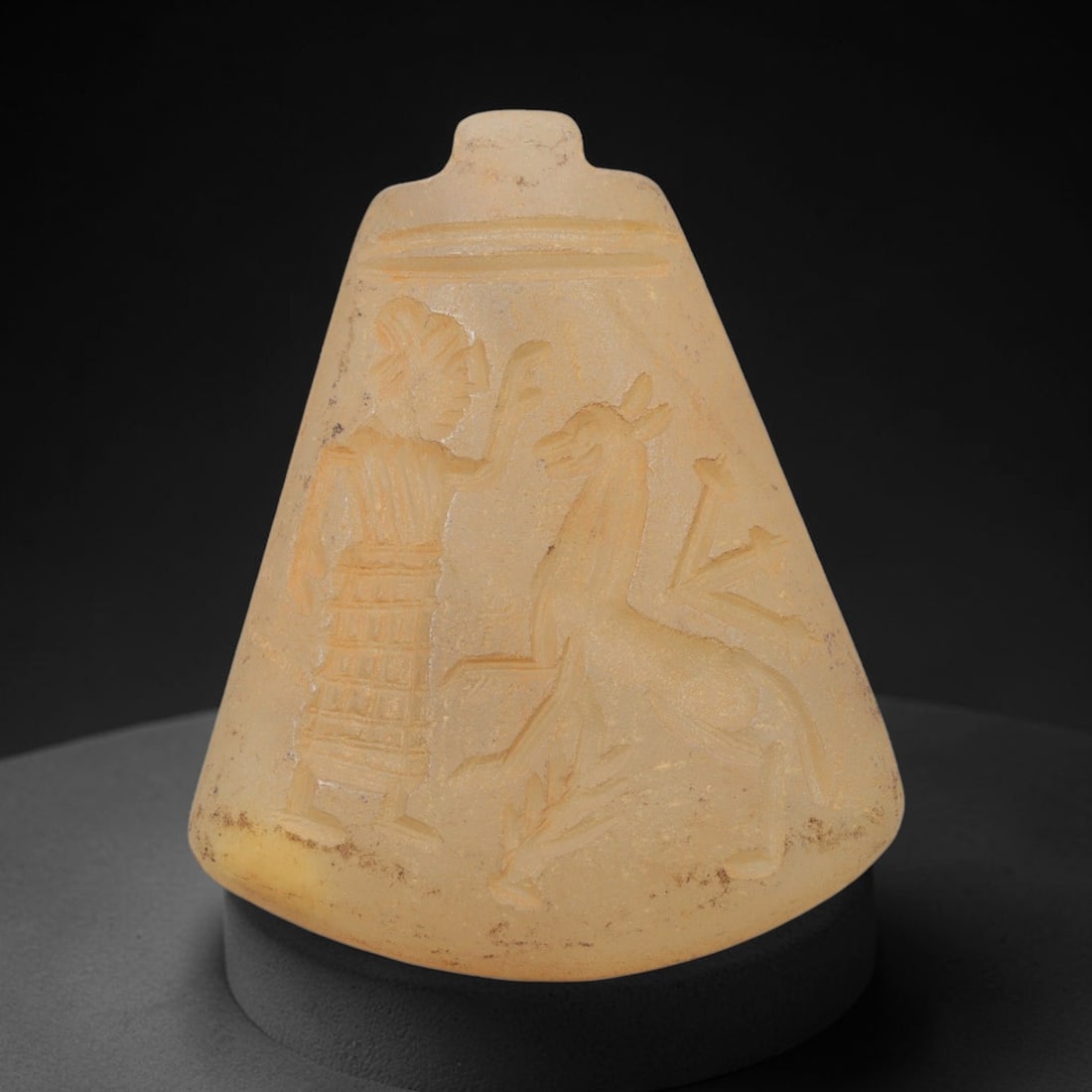 Ancient Chalcedony Amulet - Near Eastern Human & Bovid Figure, 16ZX: Carved from chalcedony, this amulet features a relief scene depicting a standing human figure interacting with a recumbent bovid, rendered in the stylized glyptic tradition of the ancient Near East. T