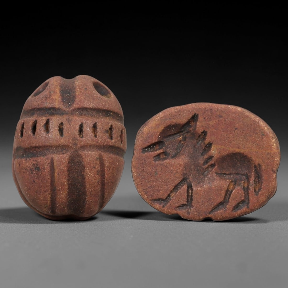 Ancient Steatite Scarab Stamp Seal - Near Eastern Jackal Figure, 74AM: Carved from reddish-brown steatite, this Near Eastern scarab stamp seal features a dorsal scarab pattern with incised linear elytra segments and decorative perforations, while the ventral face depicts