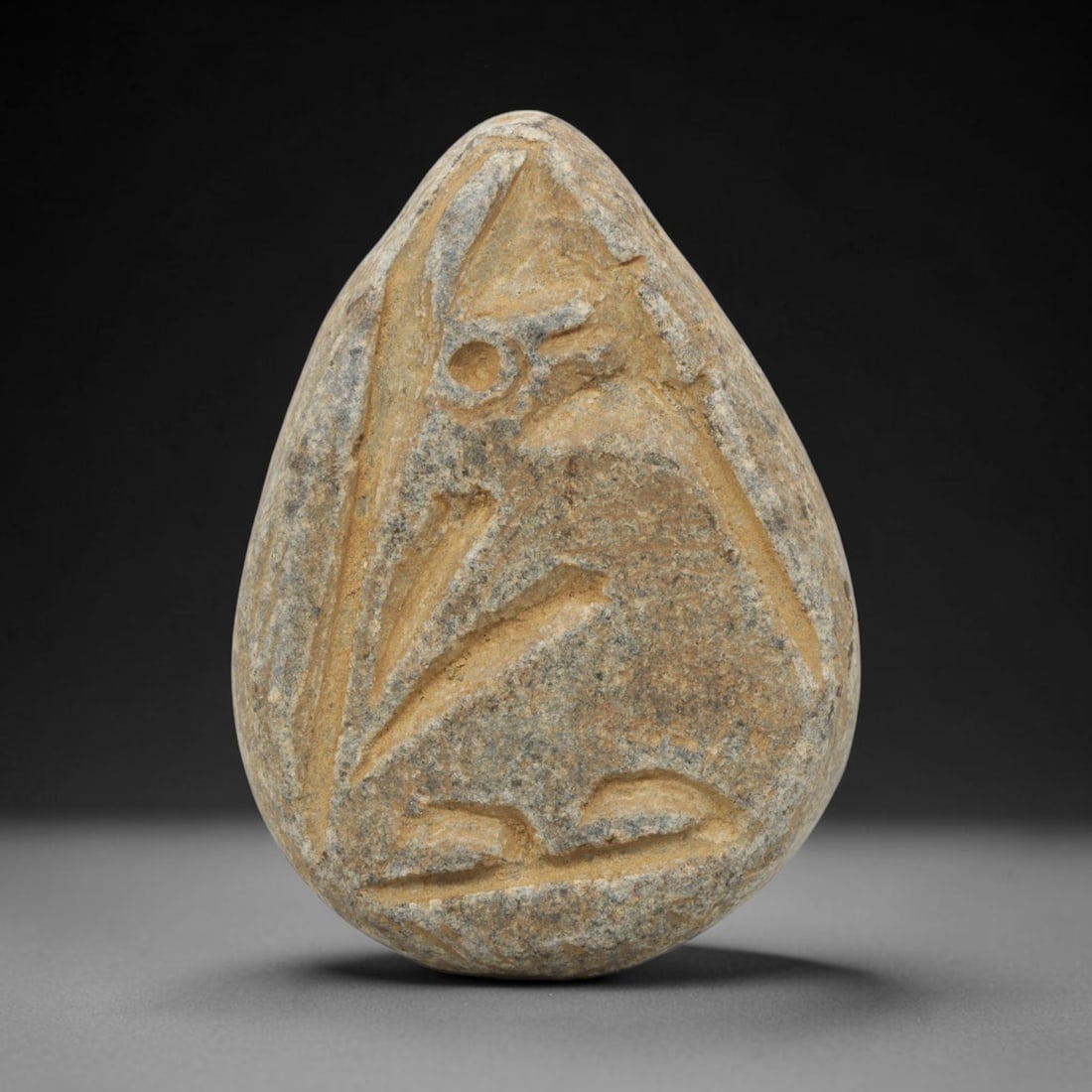 Ancient Near Eastern Schist Ibex Amulet Plaque, 52ZX: This ancient amulet is carved from a piece of schist, a metamorphic stone, in a teardrop shape. The front is incised with a stylized ibex or wild goat, depicted in a seated or crouching pose, rendered