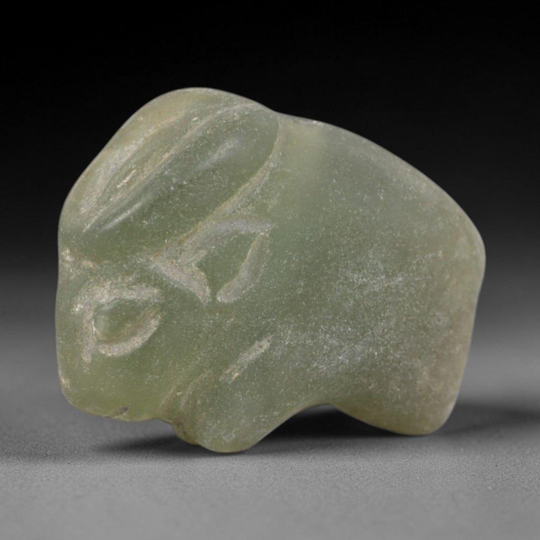 Ancient Green Stone Hare Amulet - Near Eastern Animal Figure, 34AR: Carved from pale green translucent stone, likely serpentine, this amulet depicts a stylized recumbent hare with simplified incised facial features and ear contours. The compact, rounded form emphasize