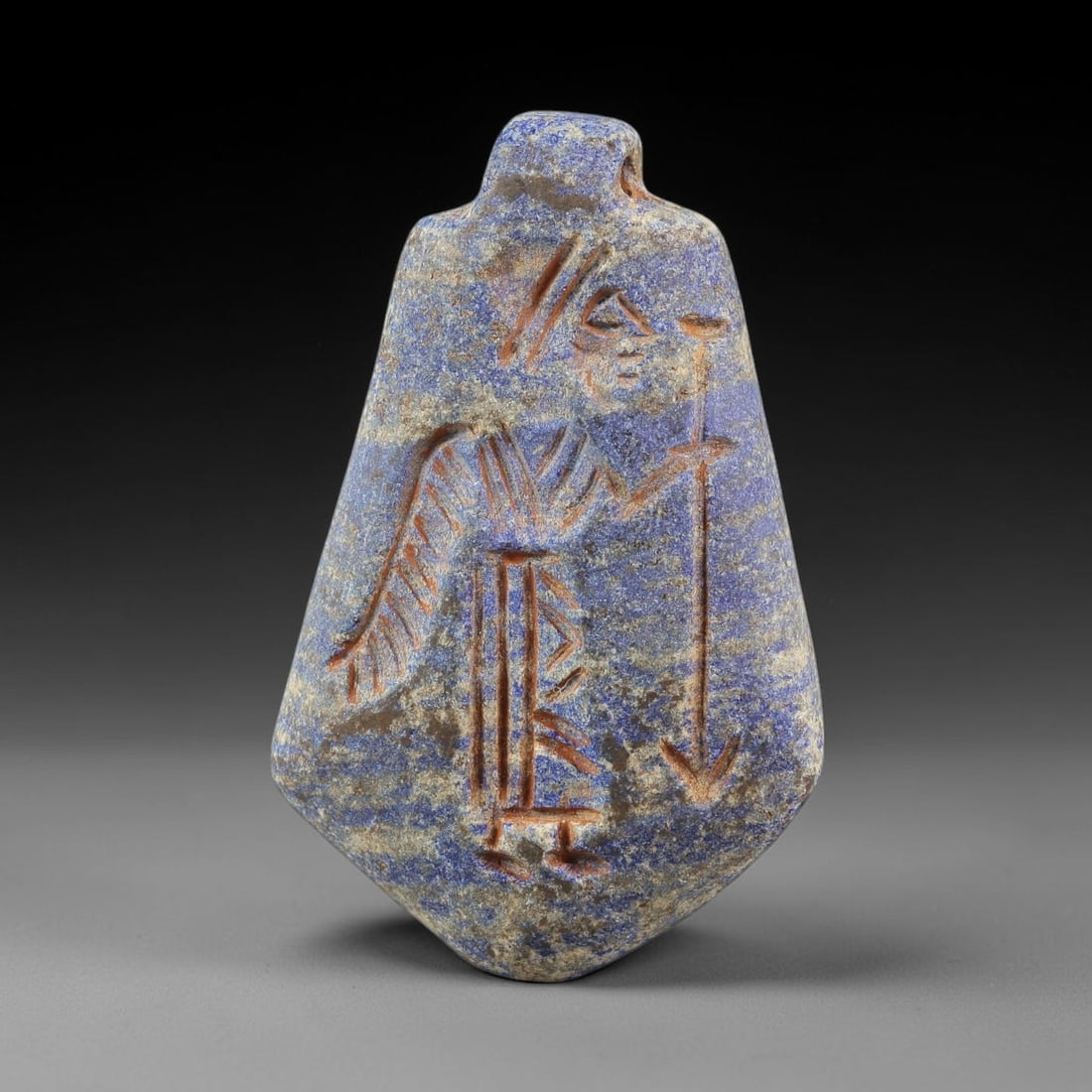 Ancient Lapis Lazuli Amulet - Near Eastern Anthropomorphic Figurine, 46BA: Carved from lapis lazuli, the amulet takes a lozenge-shaped form with a suspension loop at the top, designed for wear as a protective talisman. The front face is incised with a standing anthropomorphi