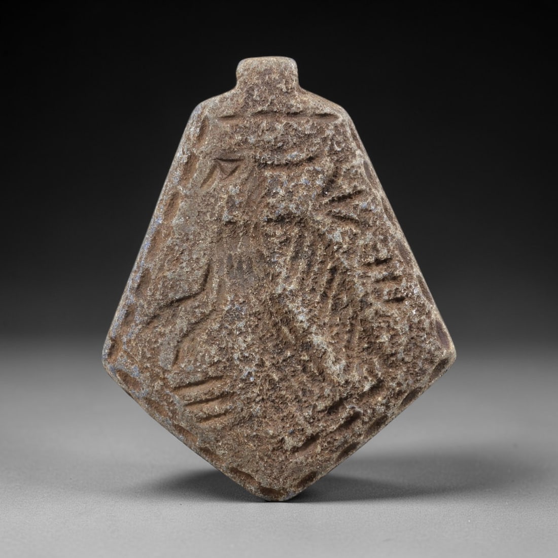 Ancient Lapis Lazuli Amulet - Near Eastern Zoomorphic Pendant, 100FX: Carved from weathered lapis lazuli, this diamond-shaped amulet features a zoomorphic form with incised linear and geometric motifs across its surface, alongside a small suspension knob at the apex for