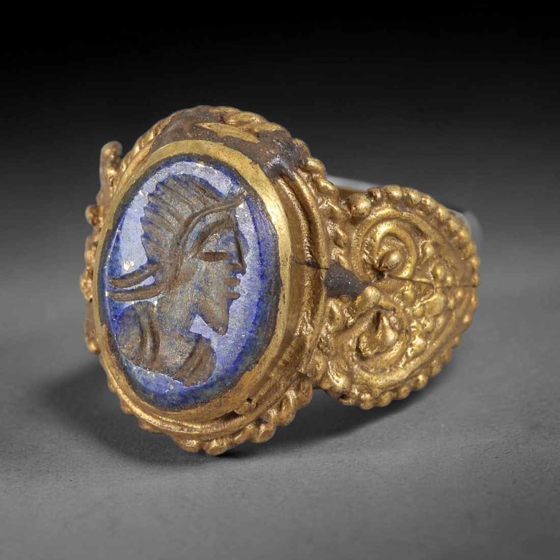 Antique Qajar Dynasty Lapis Lazuli Intaglio Ring - Size 9 US, 85FY: Crafted from gilt metal with an ornate oval bezel, this ring features a carved lapis lazuli intaglio stone at its center, depicting an incised profile portrait of a bearded figure, characteristic of Q
