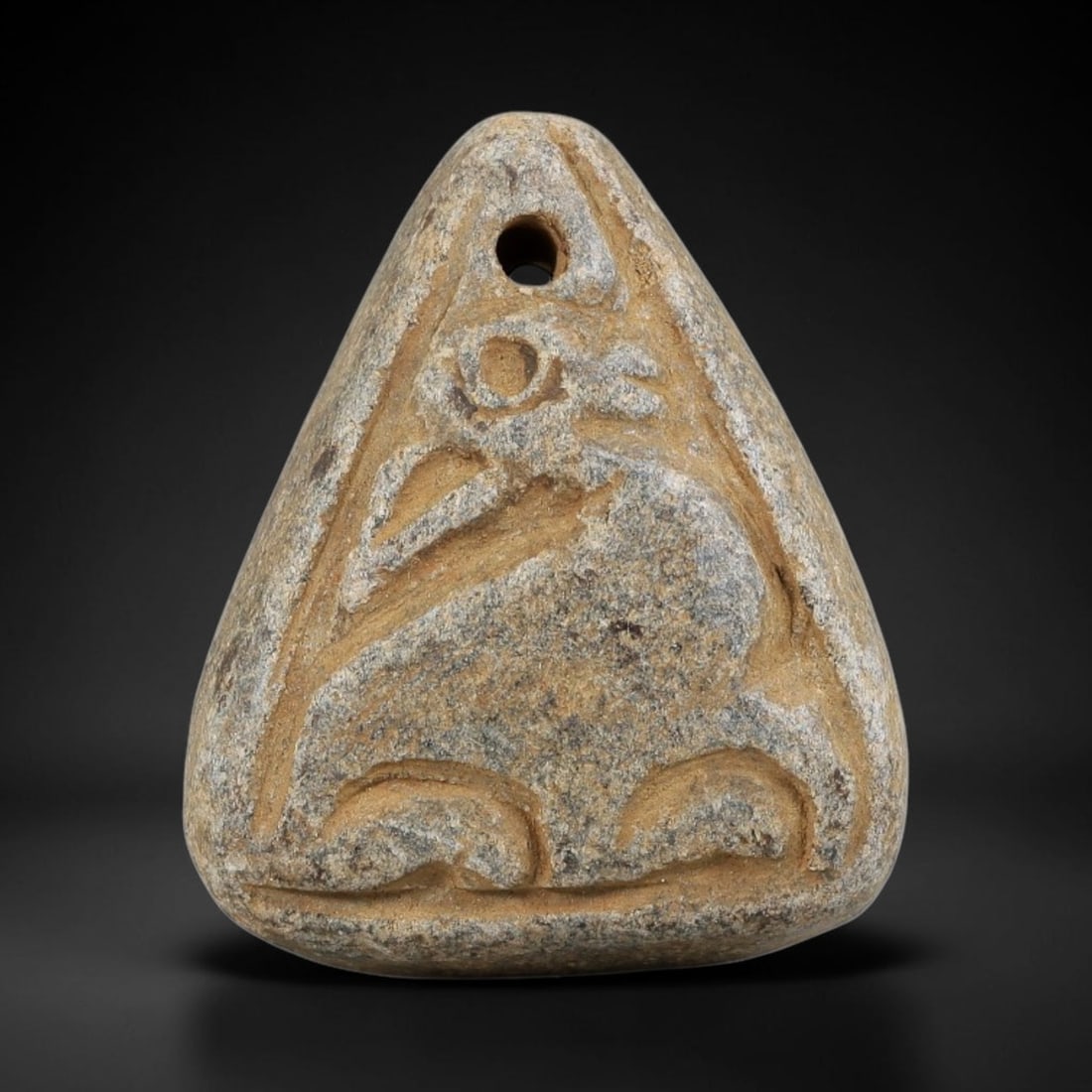 Ancient Schist Zoomorphic Amulet Pendant - Near Eastern Carved Artifact, 32BA: Carved from schist, this amulet takes the form of a triangular pendant with a rounded base, rendered in relief with bold, stylized carving. A drilled suspension hole at the top allows for wear, and th