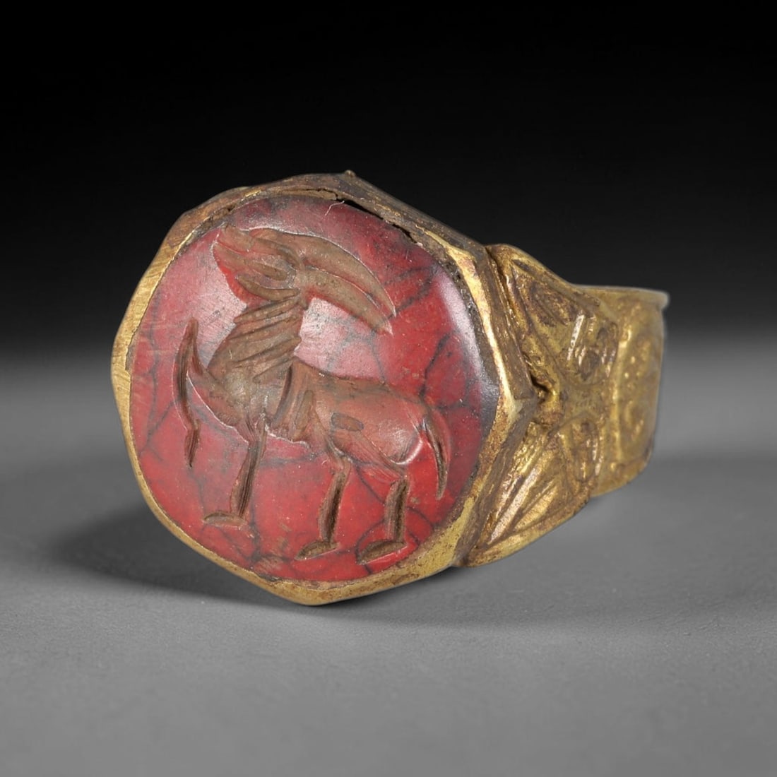 Antique Qajar Dynasty Carnelian Intaglio Brass Ring - Size 9 US, 82BA: Crafted from brass, this ring features an octagonal carnelian intaglio panel carved with a stylized ibex, executed in the traditional Qajar style. The brass band displays ornate, relief-carved metalwo