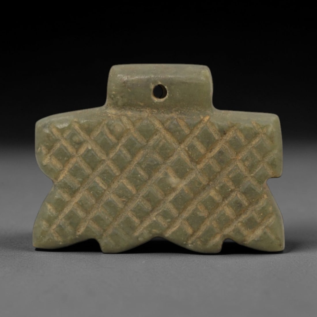 Ancient Near Eastern Serpentine Amulet - Geometric Motif, 69XQ: Carved from serpentine, this amulet features an intricate geometric lattice pattern, a hallmark of ancient Near Eastern decorative art. The piece exhibits a natural light green patina with minor surfa