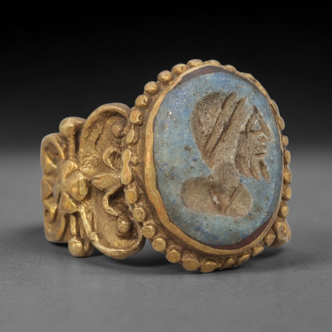 Antique Qajar Dynasty Lapis Intaglio Ring - Size 10 US, 80ZX: Crafted from gilt brass with a rounded bezel, this ring features a carved lapis lazuli intaglio stone at its center, depicting an incised profile portrait motif characteristic of Qajar-era Persian sym