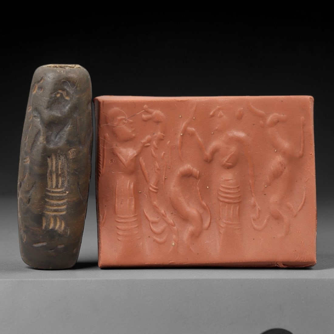 Ancient Steatite Cylinder Seal - Mesopotamian Figural & Animal Ritual Scene, 76AN: Carved from dense steatite, this ancient Mesopotamian cylinder seal features a detailed linear relief composition of two human figures interacting with animal and botanical motifs, executed in the cha