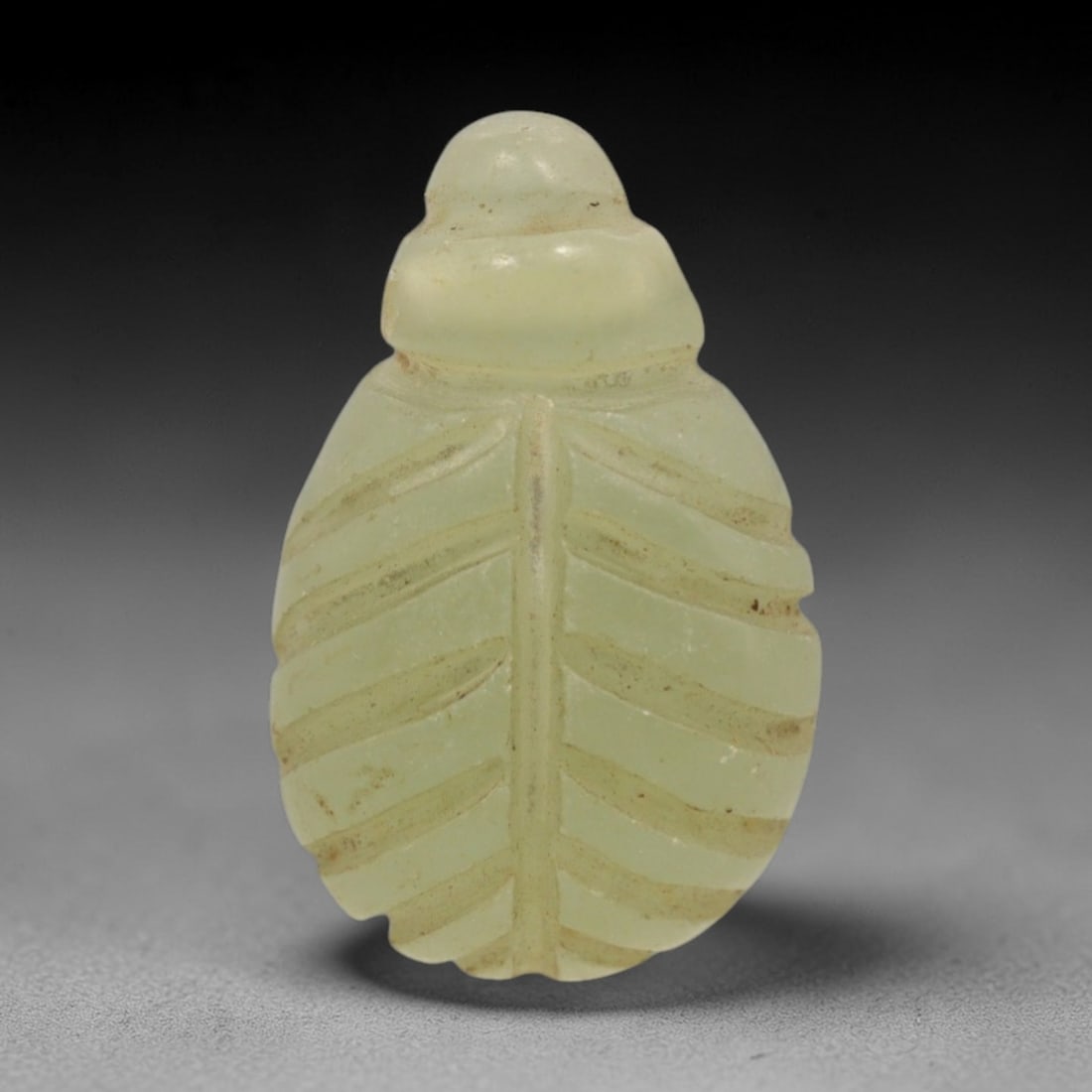 Ancient Egyptian Serpentine Scarab Amulet - Carved Pendant Figure, 82ZW: This amulet is carved from a pale, luminous green serpentine stone, with incised linear details defining its iconic scarab form. The piece features a rounded, segmented head and an oval body adorned w
