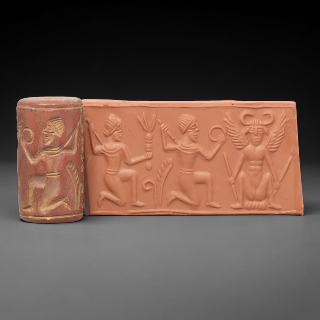 Ancient Steatite Cylinder Seal - Mesopotamian Winged Deity Scene, 35AL: Carved from richly patinated steatite, this ancient Mesopotamian cylinder seal depicts a detailed ritual scene, executed with meticulous glyptic craftsmanship characteristic of Mesopotamian Bronze Age