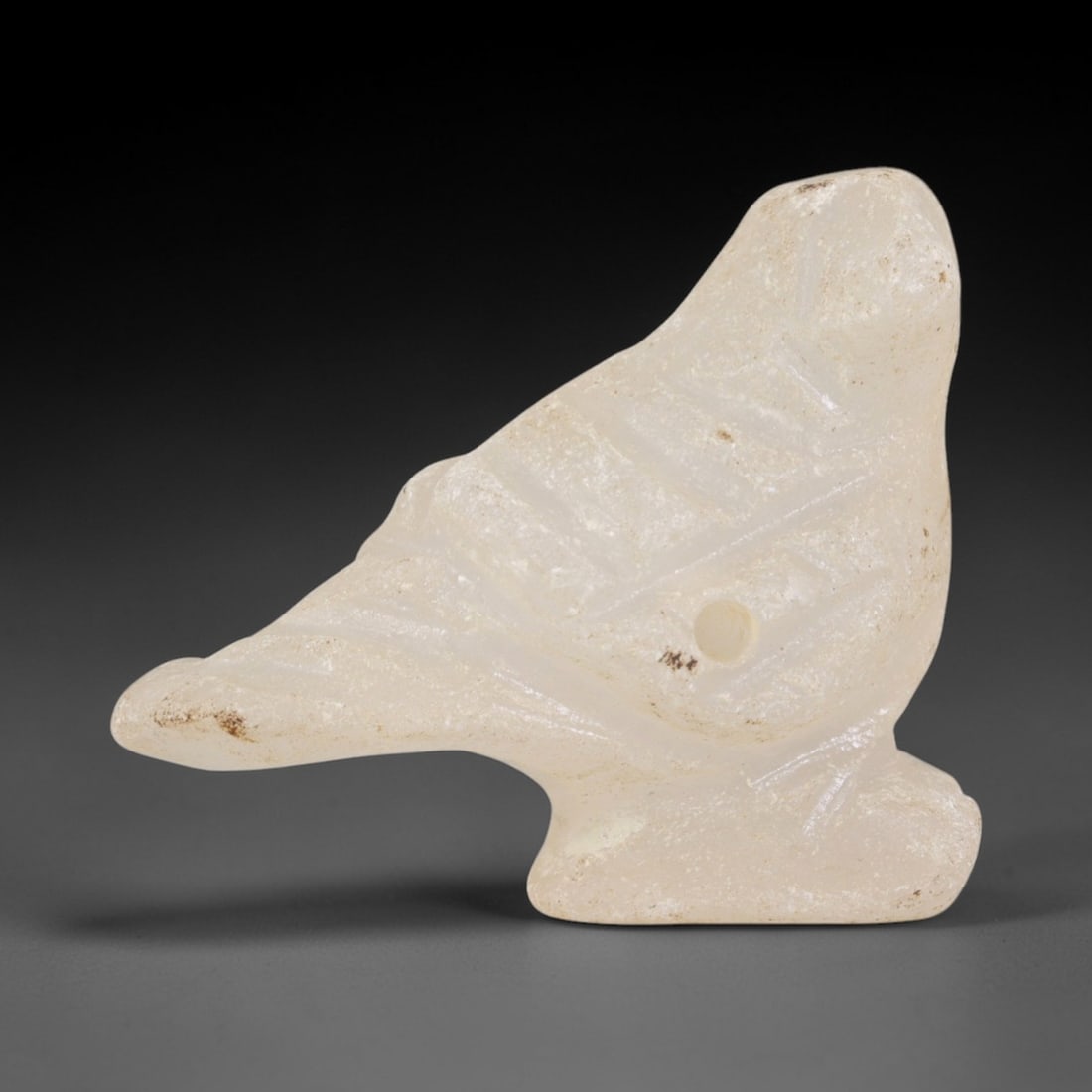 Ancient Rock Crystal Bird Amulet - Near Eastern Ritual Pendant, 66AR: Carved from translucent rock crystal, this bird amulet follows a stylized avian form with incised linear details defining wing feathers, tail, and facial contours. A pierced hole through the body conf