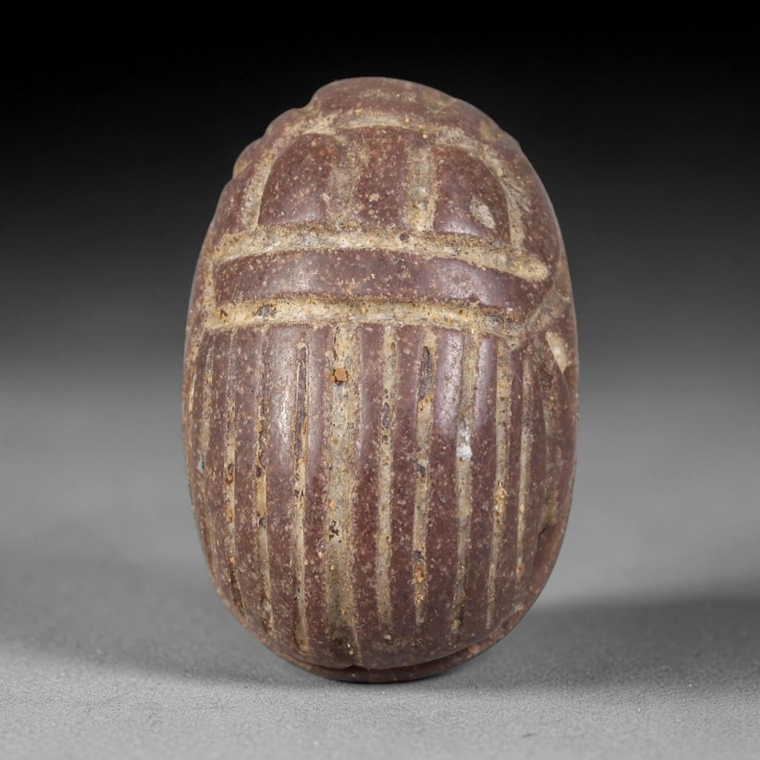 Ancient Steatite Scarab Amulet - Egyptian Figurine, 43AP: This artifact is carved from rich reddish-brown steatite, exhibiting a granular, matte finish with subtle surface wear and mineral inclusions consistent with age. The form is a classic scarab amulet,