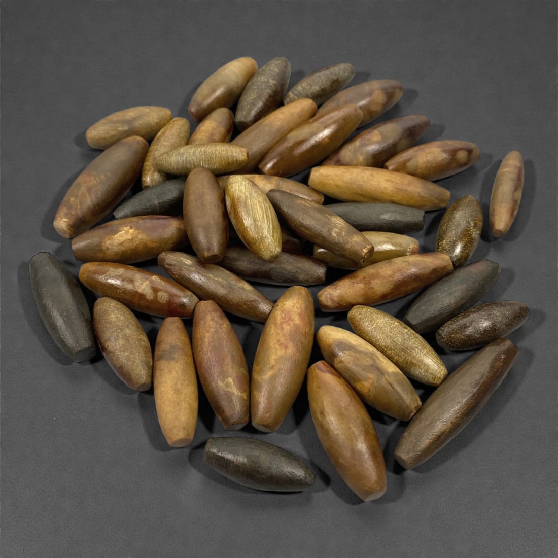A Group of Himalayan Fossilized Wood Bead Blanks, 20th Century, 41V: Comprising forty-one elongated bead blanks carved from fossilized wood, the group includes tapered and cylindrical forms with rounded ends, left undrilled and displaying natural variation in size, col
