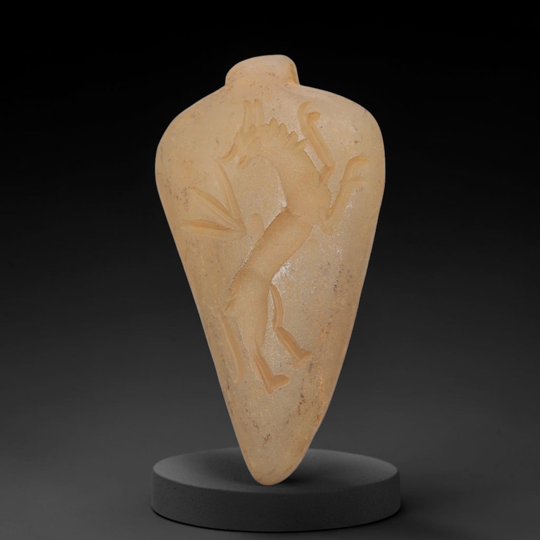 Ancient Chalcedony Amulet - Near Eastern Griffin Figure, 55ZX: Carved from translucent chalcedony, this amulet features a relief depiction of a rampant griffin, a mythical hybrid creature, rendered in the stylized glyptic tradition of the ancient Near East. The f